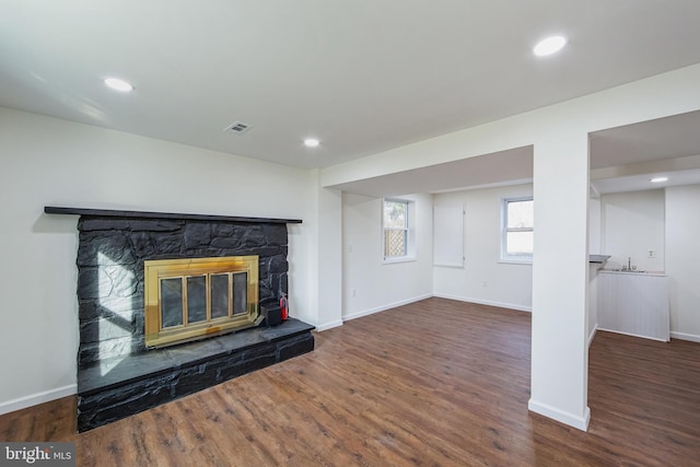 unfurnished living room with a fireplace, dark wood-type flooring, and sink