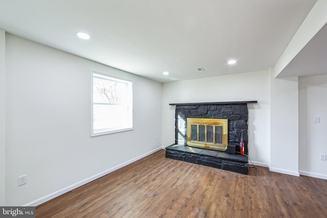 unfurnished living room featuring hardwood / wood-style floors and a stone fireplace