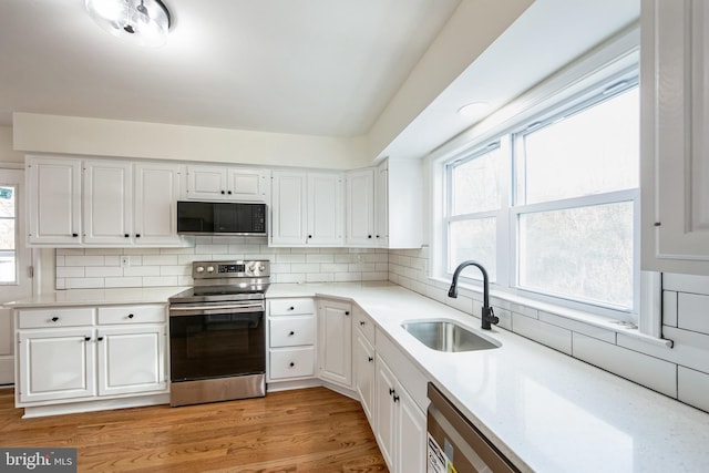 kitchen with electric stove, white cabinetry, sink, and light hardwood / wood-style flooring