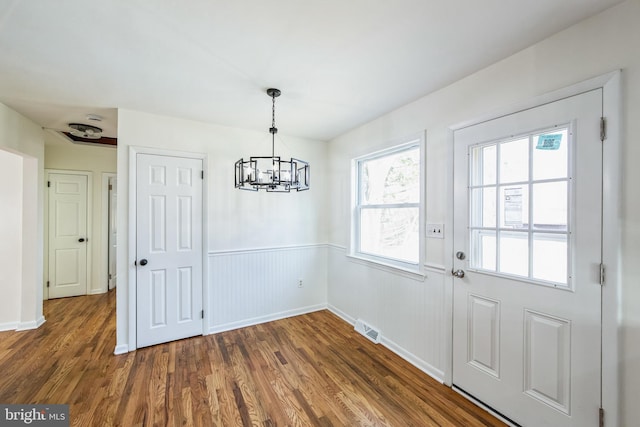 unfurnished dining area featuring a chandelier and dark wood-type flooring