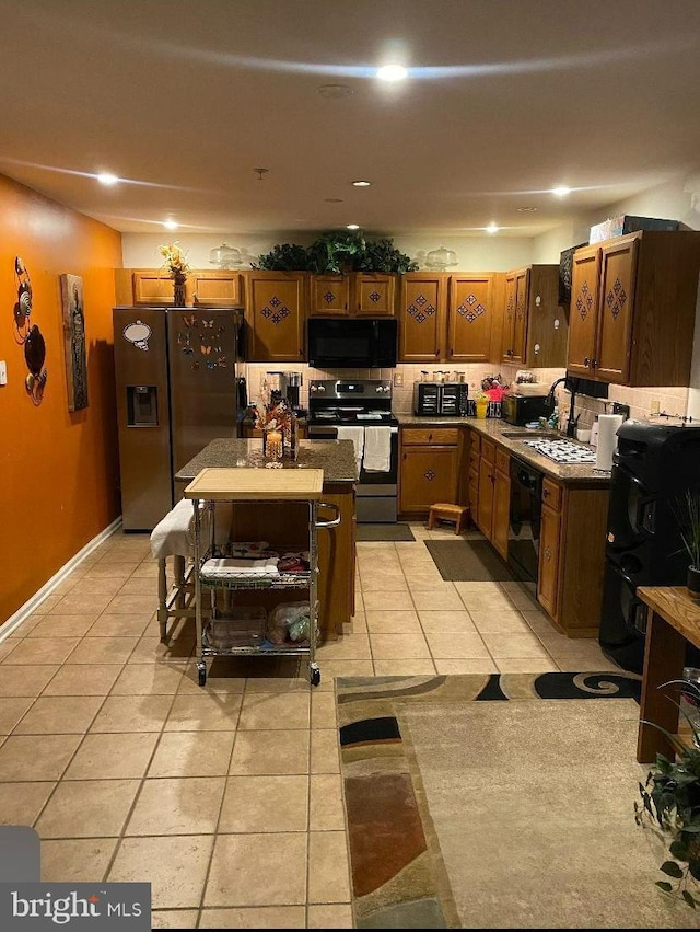 kitchen featuring black appliances, a kitchen island, light tile patterned floors, and sink