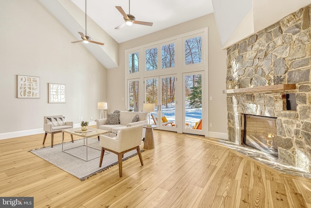 living room featuring wood-type flooring, a high ceiling, a fireplace, and ceiling fan