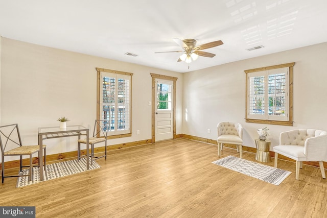 sitting room featuring wood-type flooring, ceiling fan, and a healthy amount of sunlight