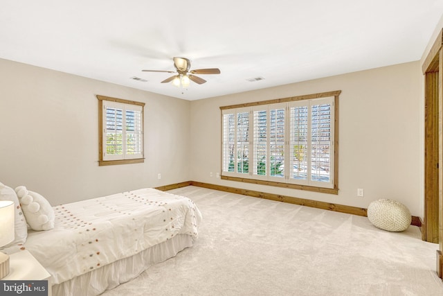 carpeted bedroom with ceiling fan and multiple windows