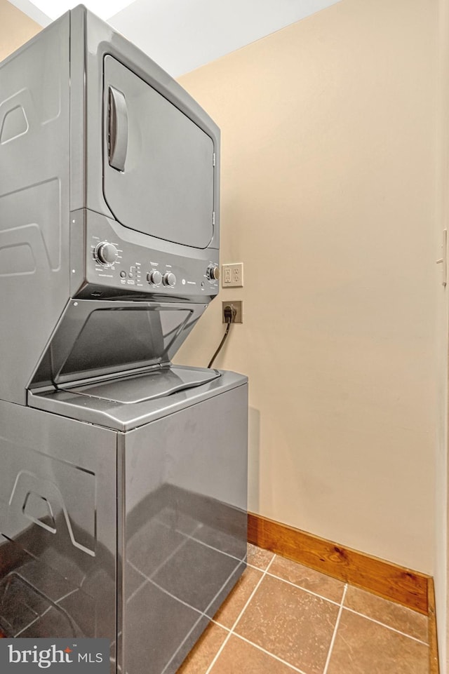 laundry area with stacked washing maching and dryer and tile patterned flooring