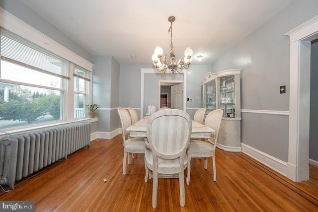 dining area featuring radiator, hardwood / wood-style floors, and a chandelier