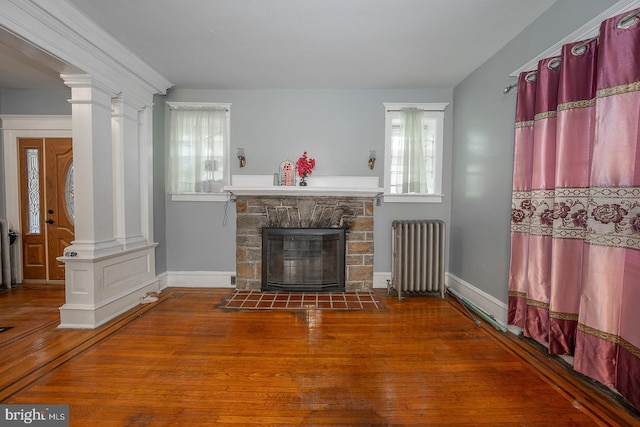 living room with radiator, a stone fireplace, and dark wood-type flooring