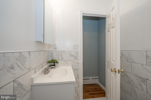 bathroom featuring hardwood / wood-style floors, vanity, tile walls, and a baseboard heating unit