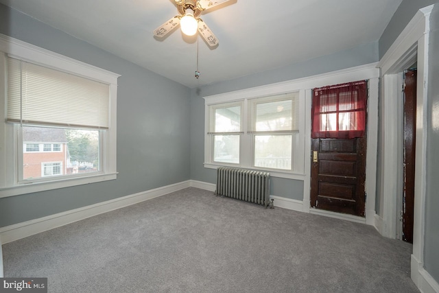 carpeted foyer with radiator heating unit, a wealth of natural light, and ceiling fan