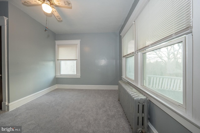 carpeted empty room with radiator heating unit and ceiling fan