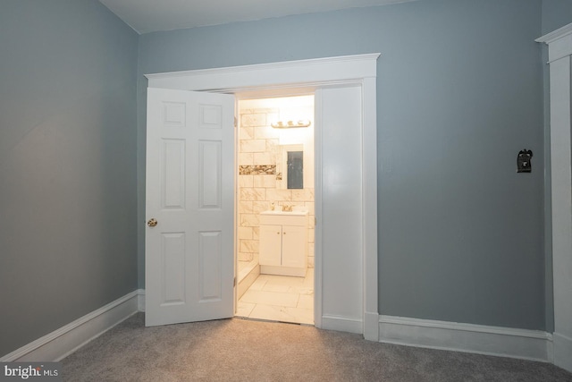 unfurnished bedroom featuring carpet flooring, sink, and ensuite bath