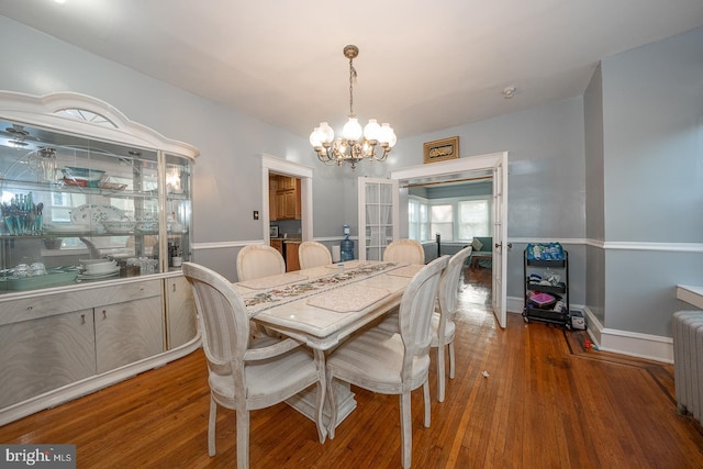 dining space with radiator, dark wood-type flooring, and a notable chandelier