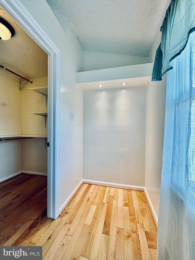 walk in closet featuring hardwood / wood-style floors and vaulted ceiling