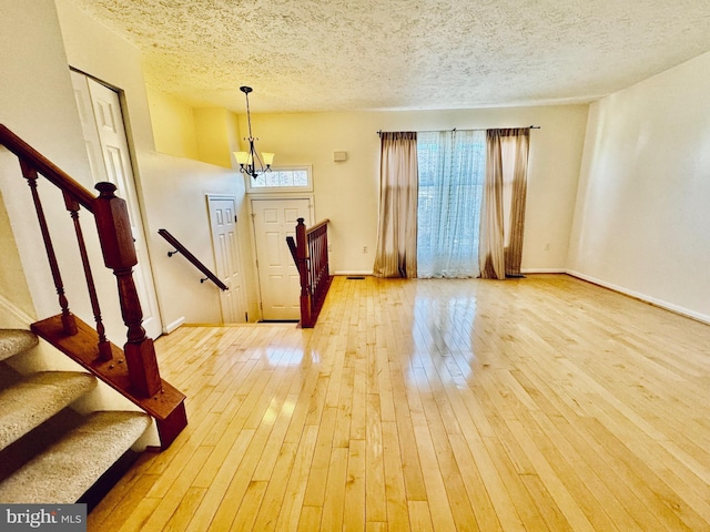 foyer featuring a chandelier, wood-type flooring, and a textured ceiling