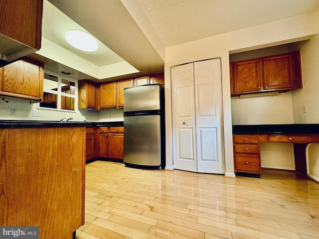 kitchen featuring a textured ceiling, stainless steel refrigerator, and light hardwood / wood-style flooring