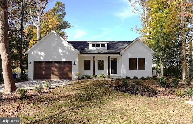 modern inspired farmhouse with covered porch, a front yard, and a garage