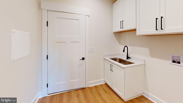 laundry room with cabinets, sink, washer hookup, and light hardwood / wood-style flooring