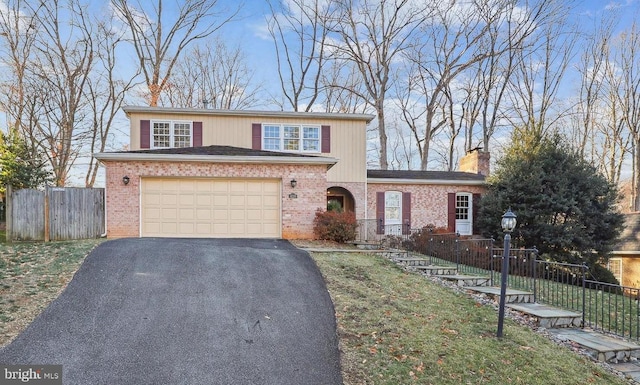 traditional-style house featuring fence, driveway, a chimney, a garage, and brick siding