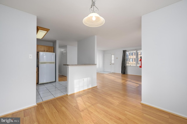 kitchen featuring pendant lighting, white refrigerator, and light hardwood / wood-style flooring