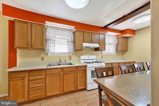 kitchen featuring beamed ceiling, light hardwood / wood-style flooring, sink, and gas range gas stove