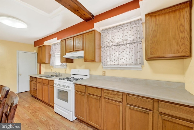 kitchen featuring beam ceiling, white gas range oven, light hardwood / wood-style floors, and sink