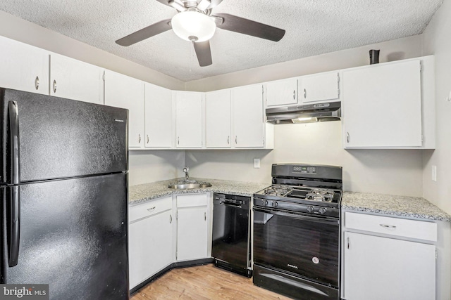 kitchen with light hardwood / wood-style flooring, white cabinets, black appliances, and a textured ceiling