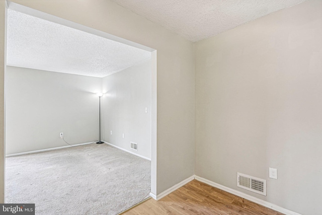 unfurnished room with hardwood / wood-style floors and a textured ceiling