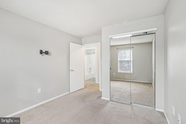 unfurnished bedroom with a closet, light colored carpet, and a textured ceiling