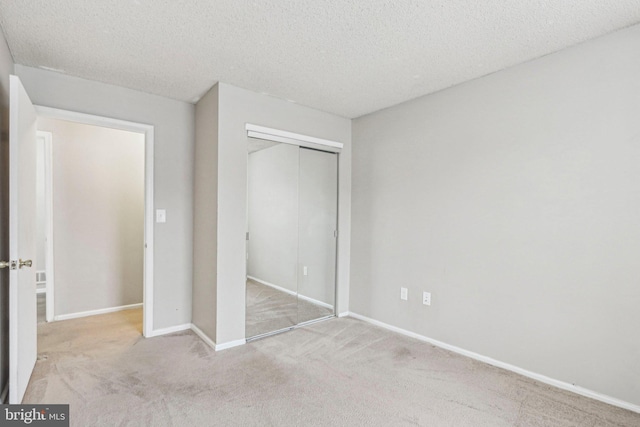 unfurnished bedroom featuring a closet, light colored carpet, and a textured ceiling