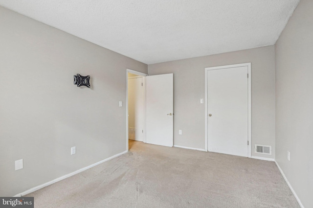 unfurnished bedroom with light colored carpet and a textured ceiling