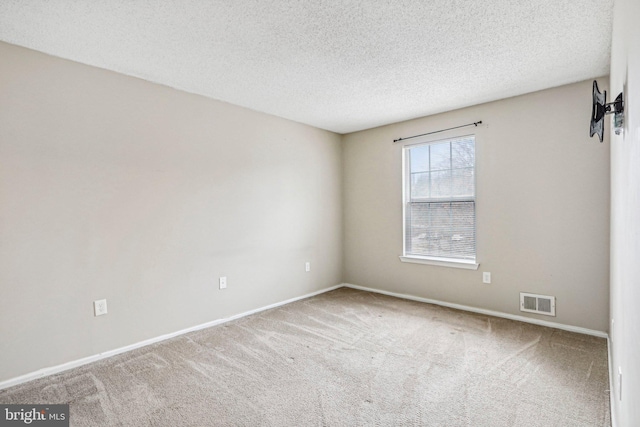 carpeted empty room featuring a textured ceiling