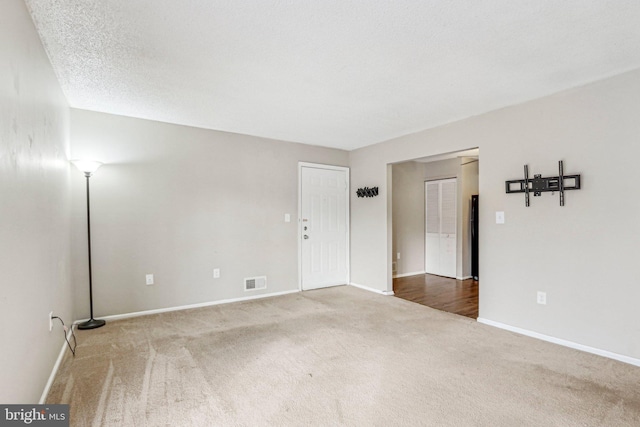 carpeted empty room with a textured ceiling