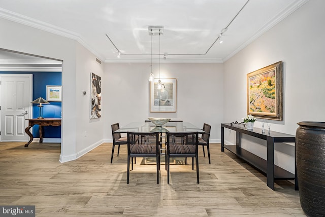 dining space with rail lighting, light wood-type flooring, and ornamental molding