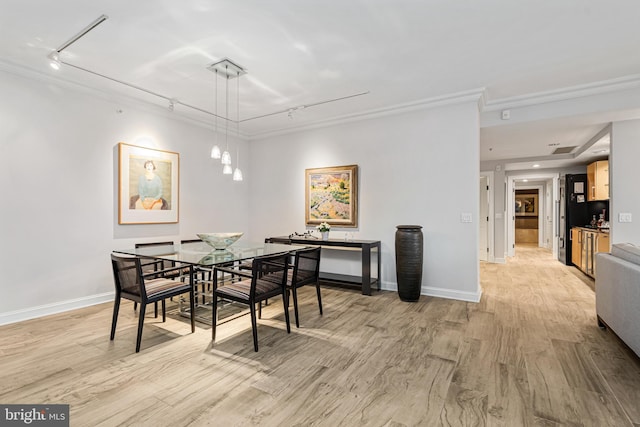 dining space with rail lighting, light hardwood / wood-style flooring, and crown molding