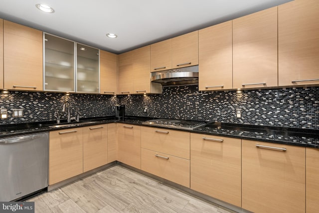 kitchen featuring appliances with stainless steel finishes, tasteful backsplash, sink, light brown cabinets, and dark stone countertops