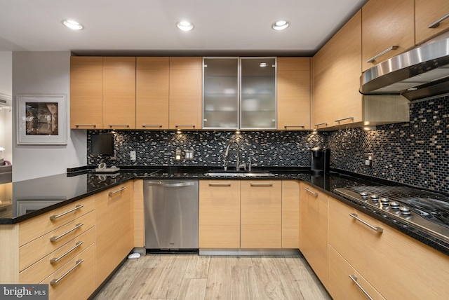 kitchen with dishwasher, light brown cabinets, ventilation hood, dark stone countertops, and gas cooktop