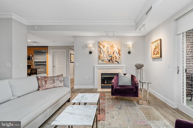 living room featuring wood-type flooring and crown molding