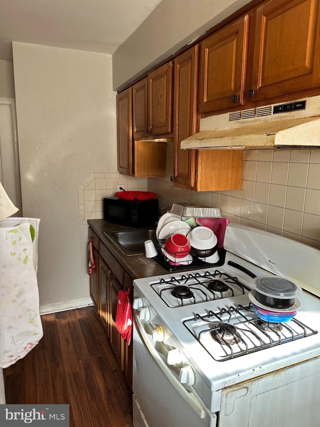 kitchen featuring dark hardwood / wood-style flooring, decorative backsplash, and white gas stove