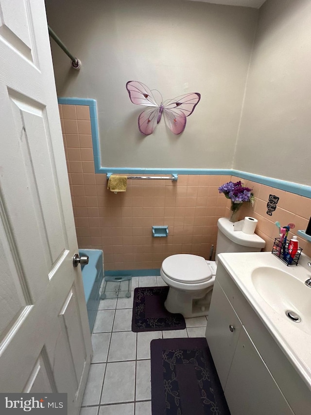 bathroom featuring tile patterned flooring, vanity, tile walls, and toilet