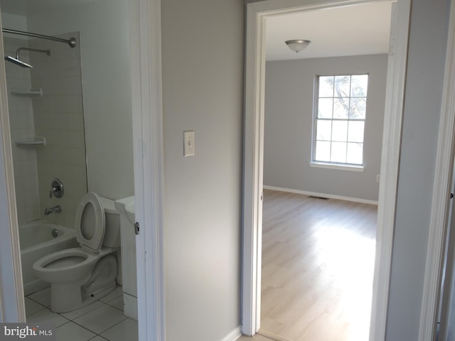 bathroom with tile patterned floors, toilet, and tiled shower / bath