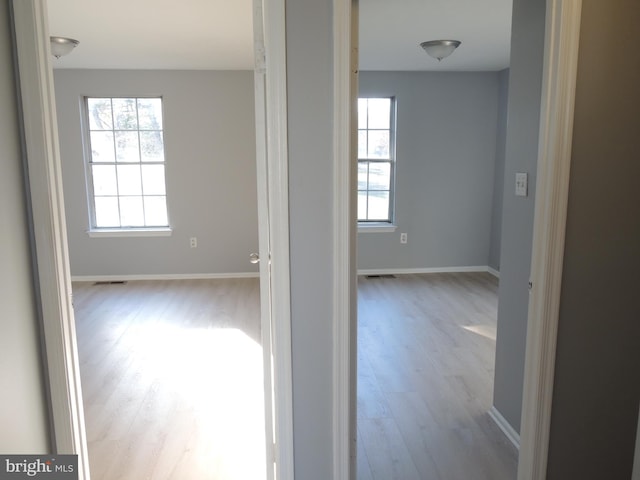 corridor with a healthy amount of sunlight and light hardwood / wood-style floors