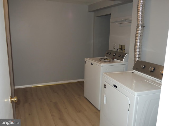 laundry area with separate washer and dryer and light hardwood / wood-style floors