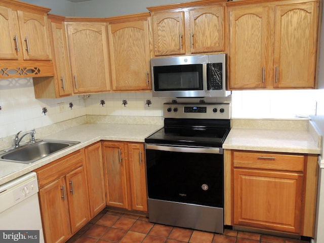 kitchen with tasteful backsplash, sink, dark tile patterned floors, and stainless steel appliances