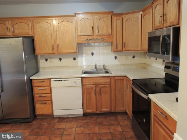 kitchen with dark tile patterned flooring, decorative backsplash, sink, and stainless steel appliances