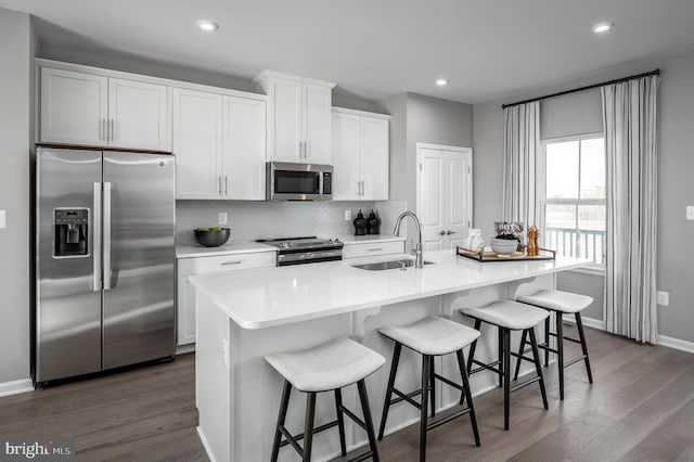 kitchen with a kitchen island with sink, sink, white cabinets, and stainless steel appliances