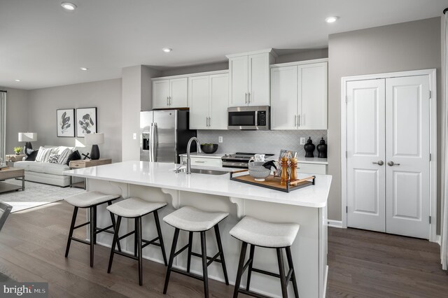 kitchen featuring a breakfast bar, dark hardwood / wood-style flooring, a kitchen island with sink, and appliances with stainless steel finishes