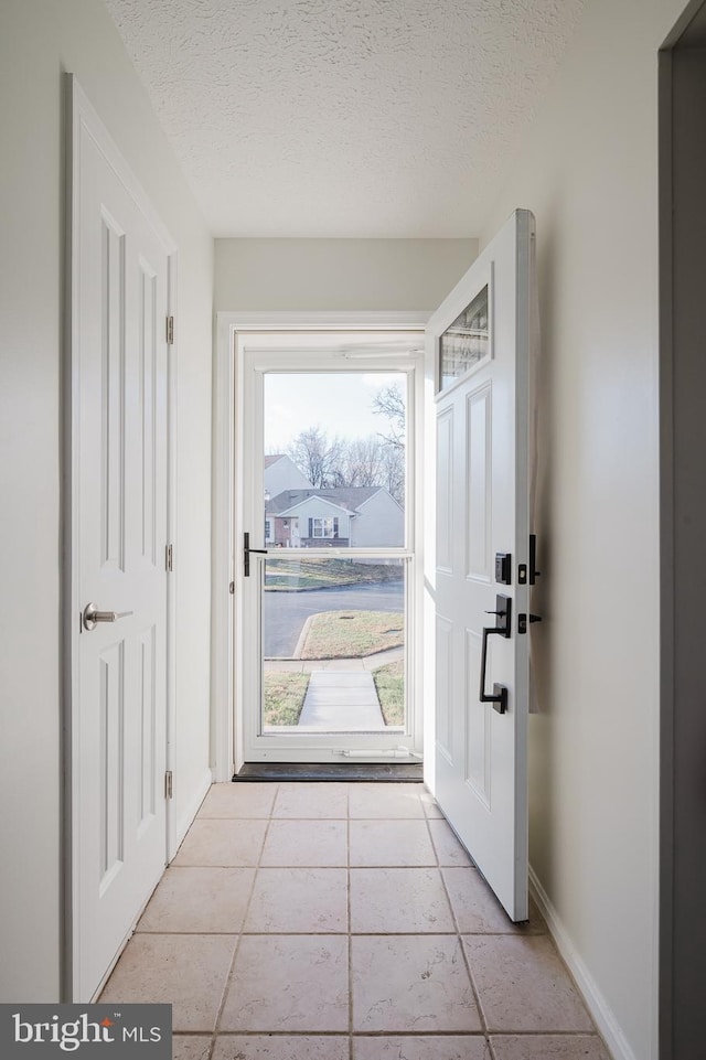 doorway to outside featuring a textured ceiling