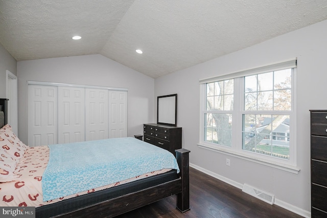 bedroom featuring lofted ceiling, a textured ceiling, dark hardwood / wood-style flooring, and a closet