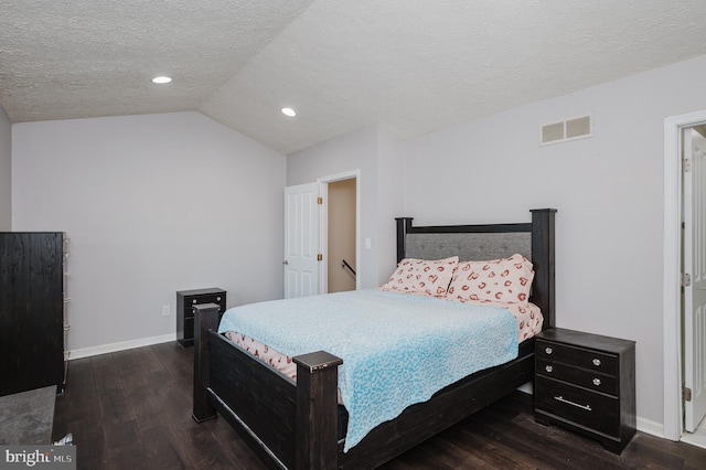 bedroom with dark wood-type flooring, vaulted ceiling, and a textured ceiling