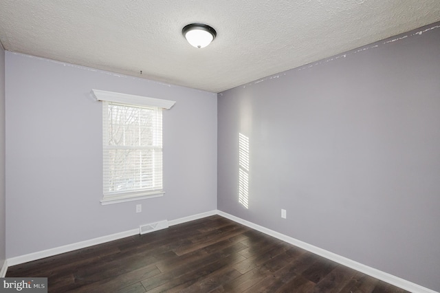 empty room with dark hardwood / wood-style floors and a textured ceiling